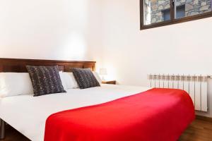 a bedroom with a white bed with a red blanket at Vista Tarter Apartments in El Tarter