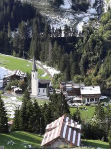 eine kleine weiße Kirche mit einem Kirchturm in einem Dorf in der Unterkunft Alpha Apartment in Schröcken