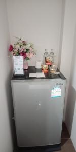 a small refrigerator with flowers on top of it at เคทู เกสเฮาส์ (K2 Guesthouse) in Chon Buri