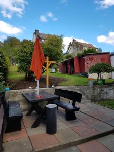 einem Picknicktisch mit einem orangenen Regenschirm und einem Kreuz in der Unterkunft Haus Bergeshöh in Braunlage