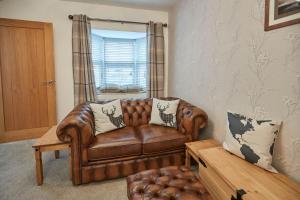 a brown leather couch in a living room with a window at Host & Stay - No 5 Hoggarths Yard in Whitby