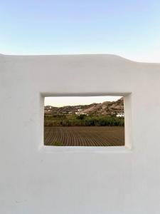 a window in a white wall with a field at Ploes Seaside Houses in Plaka
