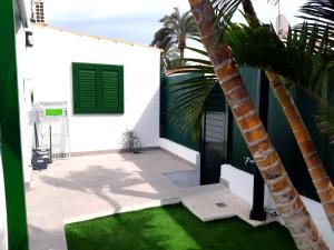 a patio with a palm tree next to a house at Tartanas 144 playa del inglés, jumbo in Playa del Ingles