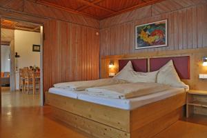 a bedroom with a large bed with a wooden wall at Alpenstern Finy, Bio-Gästehaus in Oy-Mittelberg