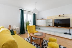 ein Wohnzimmer mit einem gelben Sofa und einem TV in der Unterkunft ap4you Tauron Cracow in Krakau