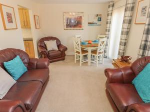 sala de estar con sofás de cuero, mesa y sillas en Ffau'r Ddraig en Llanelli