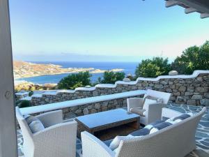a patio with chairs and a table and a stone wall at Psarou Summer Villas in Psarou