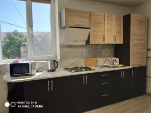 a kitchen with black cabinets and a sink and a microwave at Apartments Domovik Korzo in Mukacheve