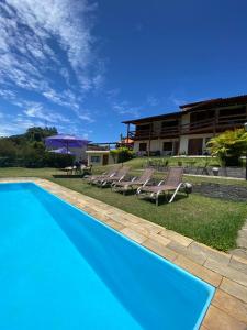 a pool with chairs and a building in the background at Pousada Village Tere in Teresópolis