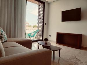 a living room with a couch and a flat screen tv at Meliora by Bunik in Playa del Carmen