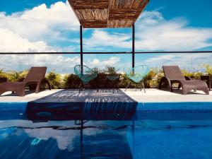 a swimming pool with two chairs and a table and chairsitures at Meliora by Bunik in Playa del Carmen