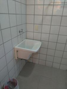uma casa de banho com um lavatório branco numa parede em azulejo em Apart Hotel Quartier Latin em Vitória