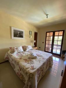 a bedroom with a bed with a flowered comforter at Pousada Village Tere in Teresópolis