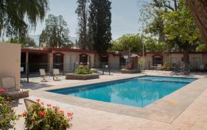 una piscina en un patio con sillas y un edificio en Hotel Huizache, en Saltillo