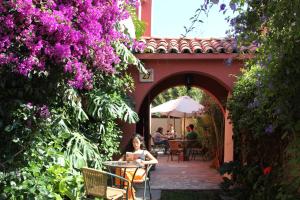 uma mulher sentada à mesa num jardim com flores roxas em El Arbol Hostel em La Serena