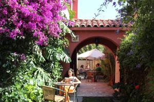 a woman sitting at a table in a garden with purple flowers at El Arbol Hostel in La Serena