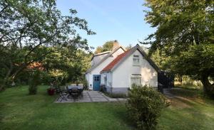 a small white house with a patio in the yard at Cottage Duinroos - Dune Rose in Oostvoorne