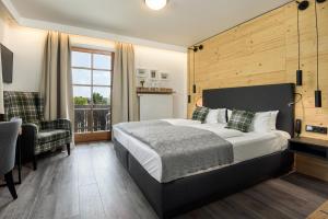 ein Schlafzimmer mit einem Bett, einem Stuhl und einem Fenster in der Unterkunft Hotel Neuer am See in Prien am Chiemsee