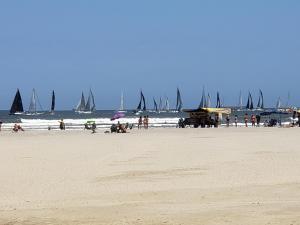 a group of people on a beach with sail boats at Apto Gonzaga Frente ao Mar Wi-Fi in Santos