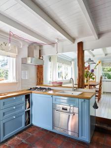 uma cozinha com armários azuis e um lavatório em Cottage Duinroos - Dune Rose em Oostvoorne