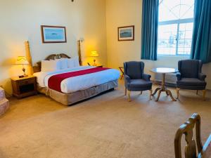 1 Schlafzimmer mit einem Bett, 2 Stühlen und einem Tisch in der Unterkunft Riveredge Resort Hotel in Alexandria Bay