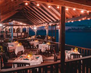 a restaurant with tables and lights on a deck at COCOS Hotel Antigua - All Inclusive - Adults Only in Bolans