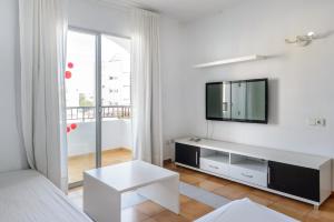 a white living room with a tv and a couch at Apartamentos San Antonio Beach in San Antonio Bay
