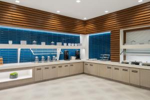 a large kitchen with brown cabinets and blue tiles at Hyatt Place Atlanta/Perimeter Center in Atlanta