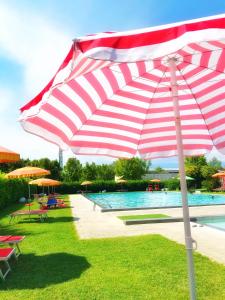 einen roten und weißen Regenschirm neben einem Pool in der Unterkunft Hotel Ca' Brugnera in Brugnera