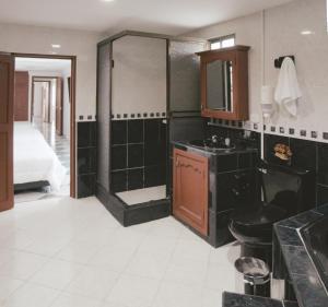 1 cama y baño con lavabo y ducha. en NOGAL HOSTEL, en Pereira