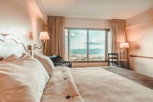 um quarto com uma cama grande e uma janela grande em Wyndham Garden Ushuaia Hotel del Glaciar em Ushuaia