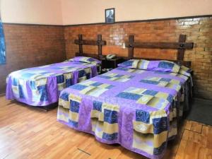 two beds in a room with a wooden floor at Hotel San Agustin in Puebla