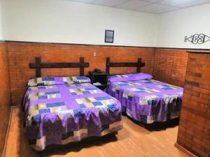 two beds in a room with a brick wall at Hotel San Agustin in Puebla