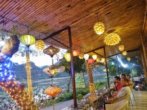 grupa ludzi siedzących przy stole ze światłami w obiekcie Trang An Lotus Lake Homestay w mieście Ninh Binh