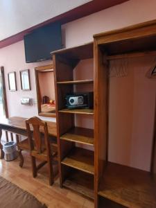 a room with a table and a book shelf with a microwave at Hotel San Angel in Puebla