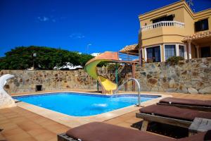 una piscina con un tobogán frente a una casa en VILLA LAS CUEVAS, en Tías