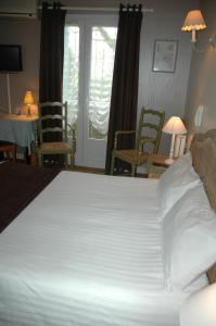 ラ・コティニエールにあるHôtel L'Ecaillerの椅子付きの客室内の大きな白いベッド