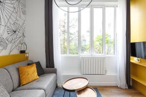 un soggiorno con divano, tavolo e finestra di Superb Mini Loft close Montmartre 2 people a Parigi