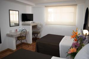 a bedroom with a bed and a desk and a television at Hotel Santiago in Puebla