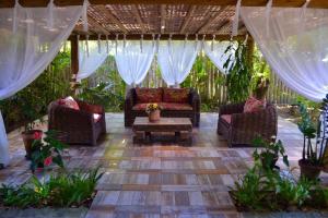 un patio con sofás, mesa de centro y cortinas en Pousada do Roballo, en Arraial d'Ajuda