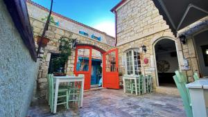 a building with an orange door and two chairs at Oberj d'Azur Alaçatı in Alaçatı