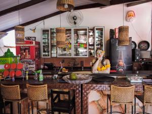a kitchen with a bar with a woman on the phone at Pousada das Seriemas in Pirenópolis