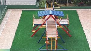 einen Spielplatz mit einer Leiter und Bänken auf dem Rasen in der Unterkunft Apartamento com piscina 1 quarto de até 6 pessoas - Guarujá in Guarujá