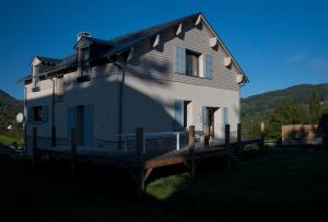 a large white house with a wooden porch at D'un jour à l'autre in Banassac