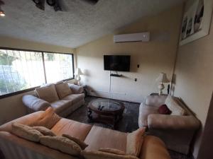 a living room with couches and a flat screen tv at La Quinta de Don Hugo in Ixtapa