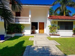 a white house with a green yard and a door at La Quinta de Don Hugo in Ixtapa