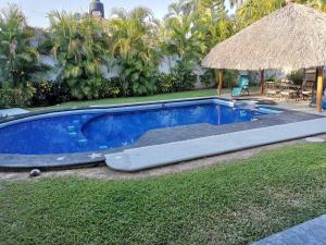 a blue swimming pool with a straw umbrella at La Quinta de Don Hugo in Ixtapa