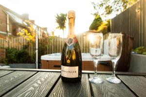 a bottle of wine and two glasses on a wooden table at Villa Neptune at Rounton Villa by Maison Parfaite - Hot Tub - Parking - Robin Hoods Bay in Robin Hood's Bay