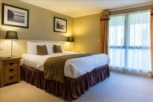 Un dormitorio con una cama grande y una ventana grande. en CELEBRATE AT THE WORLD FAMOUS LOCH LOMOND RESORT CAMERON HOUSE - Sleeps 6, en Alexandria