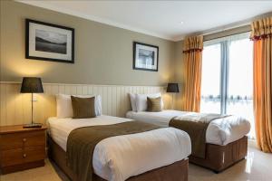 Una habitación de hotel con dos camas y una ventana. en CELEBRATE AT THE WORLD FAMOUS LOCH LOMOND RESORT CAMERON HOUSE - Sleeps 6, en Alexandria